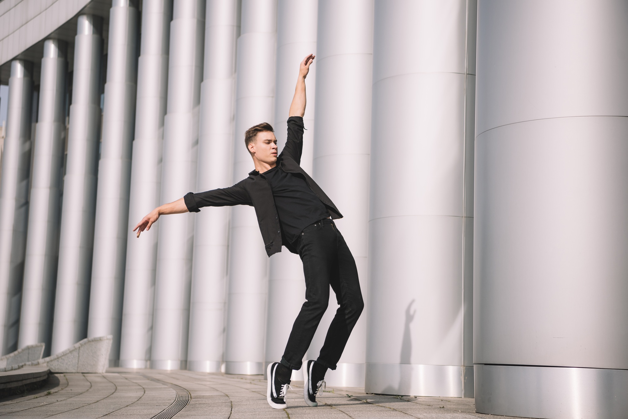 handsome young modern dancer dancing near columns